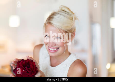 Lächelnde Frau, die rote Blume Stockfoto