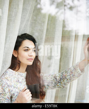 Frau trinkt Kaffee am Fenster Stockfoto