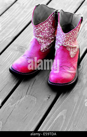 Detail der rosa Cowgirl Cowboy-Stiefel auf Holzdeck für ein Mädchen Stockfoto