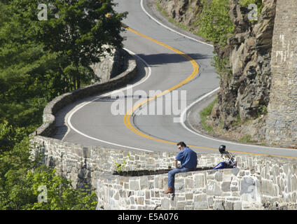 Stadt von Deerpark, New York, USA. 24. Juli 2014. Ein Motorradfahrer auf einer Felswand und nimmt in der Ansicht auf das Hawk Nest Abschnitt der Route 97 in der Stadt Deerpark, New York. Diese kurvenreiche Abschnitt der Straße, befindet sich Hunderte von Fuß über den Delaware River, wurde häufig in TV-Werbespots und Anzeigen verwendet und ist Bestandteil der oberen Delaware Scenic Byway. Bildnachweis: Tom Bushey/ZUMA Draht/Alamy Live-Nachrichten Stockfoto