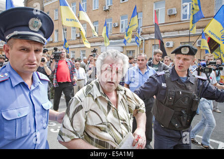 Kiew, Ukraine. 24. Juli 2014. Polizisten helfen älteren prokommunistische Mann mit Blut im Gesicht, die Website der Nationalisten Rallye in der Nähe von Kiew Verwaltungsgericht zu verlassen, die Anhörung am Verbot der kommunistischen Partei der Ukraine beginnt. Als Spannungen zwischen der Ukraine und Russland Gipfel während der Malaysia Airlines Flug 17 Untersuchung getroffen, hat ein Gericht in Kiew beschlossen, Kommunismus zu verbieten. Der Gerichtshof eine Anhörung heute bei ihrer Entscheidung zu verlangen, dass die Regierung Verbot der kommunistischen Partei der Ukraine. Bildnachweis: Sergii Kharchenko/Pacific Press/Alamy Live-Nachrichten Stockfoto