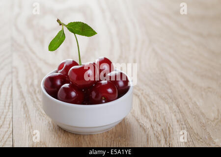 Kirsche Beeren in weiße Schale, auf rustikale Eichentisch Stockfoto