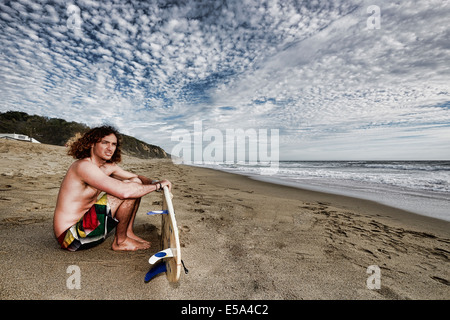 Kaukasischen Mann mit Surfbrett am Strand Stockfoto