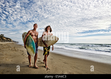 Kaukasische Männer tragen Surfbretter am Strand Stockfoto