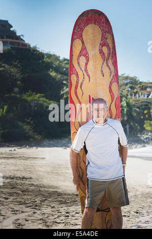 Älteren Hispanic Mann mit Surfbrett am Strand Stockfoto