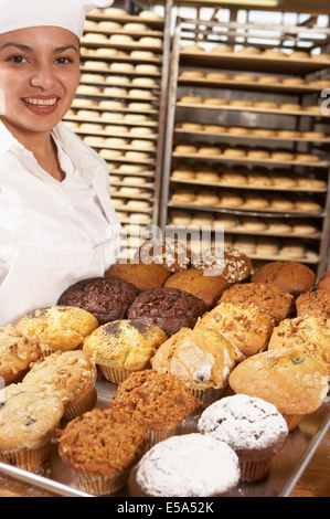 Hispanische Bäcker mit Tablett Muffins in Bäckerei Stockfoto