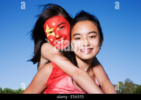 Chinesin mit chinesische Flagge gemalt auf Gesicht umarmt Freund Stockfoto