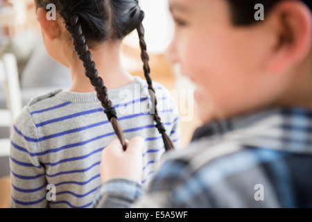 Jungen ziehen Mädchen Zöpfe Stockfoto