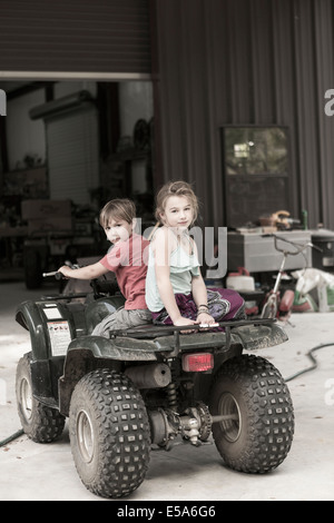 Kaukasische Kinder spielen auf vier wheeler Stockfoto