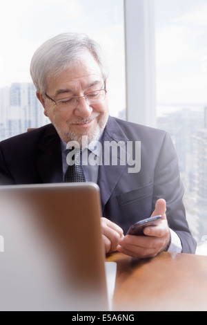 Hispano-Amerikaner Geschäftsmann mit Handy am Schreibtisch Stockfoto