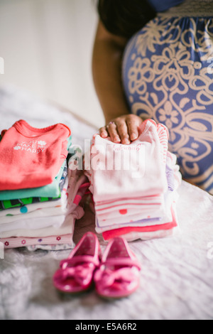 Schwangere Asiatin Faltung Babykleidung Stockfoto