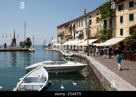 Touristen zu Fuß am Hafen vorbei in das Dorf von Lazise, Gardasee, Italien. Stockfoto