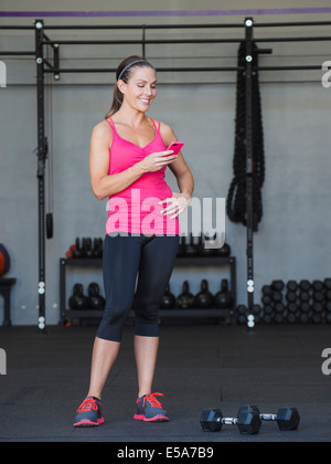 Kaukasischen Frauen mit Handy im Fitness-Studio Stockfoto