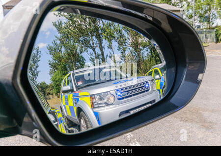 Eine Polizei Landrover mit blinkenden Lichtern in den Außenspiegel eines Autos (siehe auch E5D39J) Stockfoto