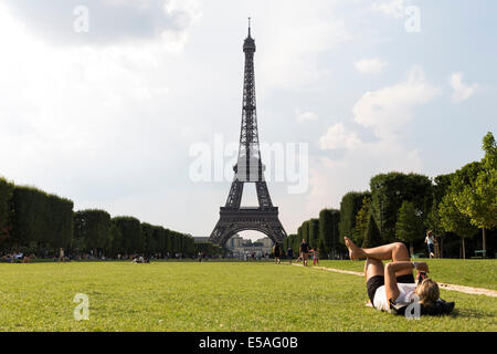 Paris, Frankreich. 24. Juli 2014. Frau, Sonnenbaden und mit ihrem Handy in Champs de Mars, Paris, Frankreich-Credit: Cecilia Colussi/Alamy Live News Stockfoto