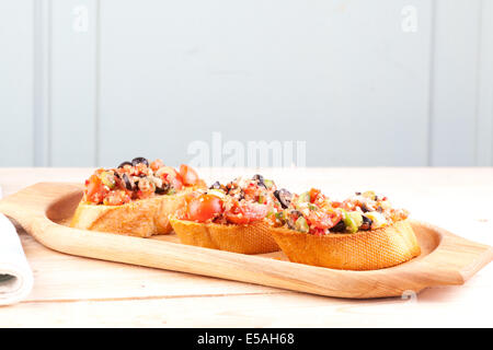 drei Stücke von Bruschetta auf Tablett aus Holz Stockfoto