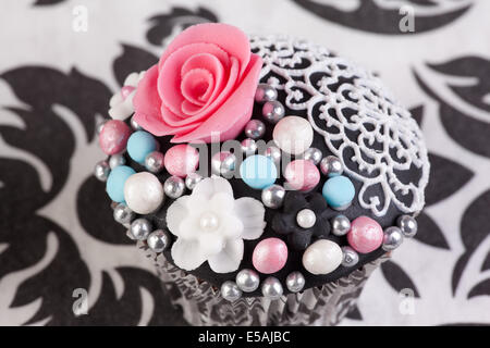Cupcake mit rosa Rose auf weißem und schwarzem Hintergrund Stockfoto