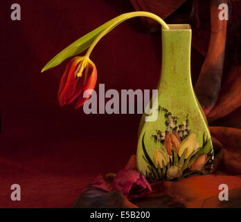 Einzelne Tulpe in einer Vintage Vase mit einer anderen Blüte an der Basis. Stockfoto