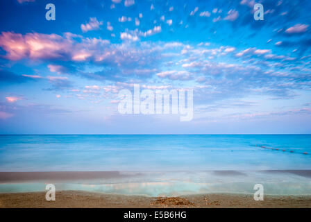 Tropischer Strand und Meer bei bewölkten Sonnenuntergang Stockfoto