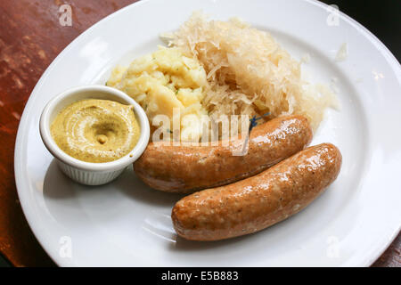 Bratwurst auf Teller mit deutschen Kartoffelsalat, Senf und sauerkraut Stockfoto