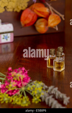 Stillleben mit drei Parfüm-Flaschen mit Blumen auf der Holzoberfläche. Stockfoto