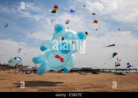 Lytham St Annes, Blackpool, 26. Juli 2014. St. Annes kite Festival. Teddybär aufblasbare Drachen in den Himmel über St Annes Strandpromenade, überschwemmt mit Farbe als fabelhafte Anzeige Drachen in der Luft auf den Strand in der Nähe der Pier. Der Himmel über St Annes Strandpromenade waren überschwemmt mit Farbe als fabelhafte Anzeige Drachen in der Luft auf den Strand in der Nähe der Pier, und mit einem riesigen blauen Aufblasbare Teddybär. Stockfoto