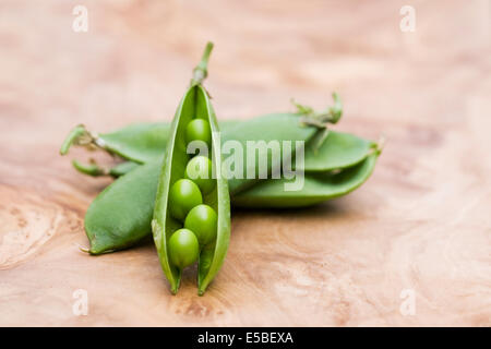 Pisum Sativum. Frisch gepflückt Erbsen auf einem Holzbrett. Stockfoto