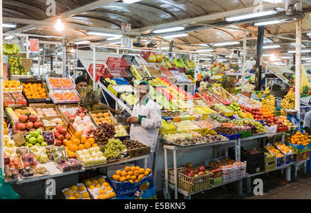 Standbesitzer ordnet die Produkte auf einem Stall Verkauf buntem Obst und Gemüse auf dem Markt durch die Fische Souk, Deira, Dubai Stockfoto