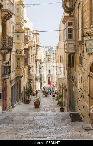 Enge Fußgängerzone gepflasterte Straße in der Innenstadt von Valletta, Malta, mit Steinplatten Treppen und historischen Gebäuden Stockfoto