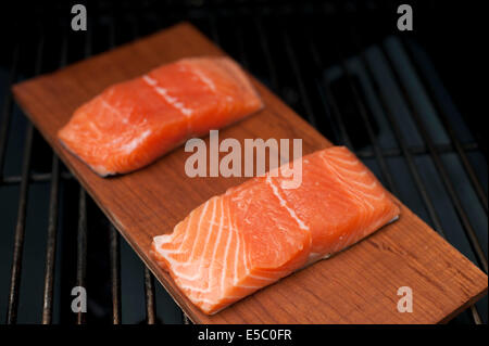 Ein paar rohe wild Alaskan Lachsfilets auf eine Zeder Planke gegrillt. Stockfoto