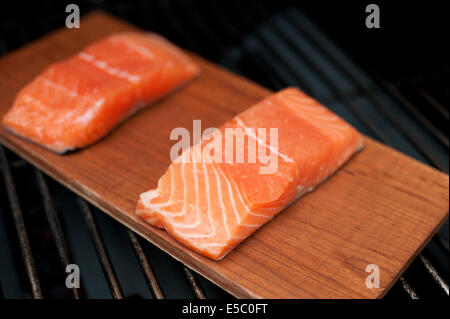 Ein paar rohe wild Alaskan Lachsfilets auf eine Zeder Planke gegrillt. Stockfoto