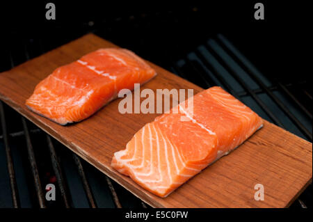 Ein paar rohe wild Alaskan Lachsfilets auf eine Zeder Planke gegrillt. Stockfoto