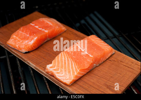 Ein paar rohe wild Alaskan Lachsfilets auf eine Zeder Planke gegrillt. Stockfoto