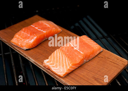 Ein paar rohe wild Alaskan Lachsfilets auf eine Zeder Planke gegrillt. Stockfoto