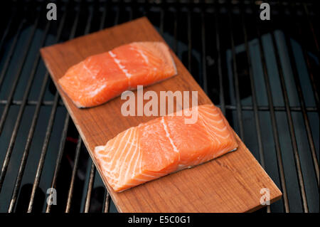 Ein paar rohe wild Alaskan Lachsfilets auf eine Zeder Planke gegrillt. Stockfoto