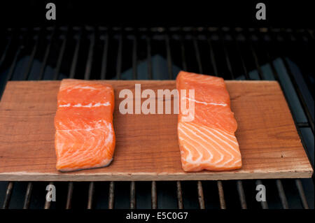 Ein paar rohe wild Alaskan Lachsfilets auf eine Zeder Planke gegrillt. Stockfoto