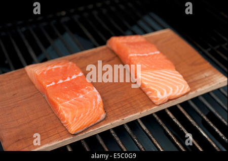 Ein paar rohe wild Alaskan Lachsfilets auf eine Zeder Planke gegrillt. Stockfoto