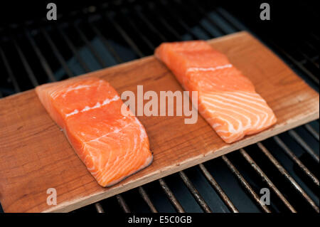 Ein paar rohe wild Alaskan Lachsfilets auf eine Zeder Planke gegrillt. Stockfoto