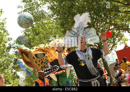 London, UK. 27. Juli 2014. Ein Mann aus der Emergency Exit Arts Tänze vor einem Karneval-Schwimmer im Queen Elizabeth Park in Newham. Bildnachweis: David Mbiyu / Alamy Live News Stockfoto