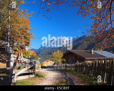 Ein Bauerndorf im Villnösser Tal (Val di Funes) mit im Hintergrund die Dolomiten Geisler im Herbst in Italien Bergspitzen. Stockfoto