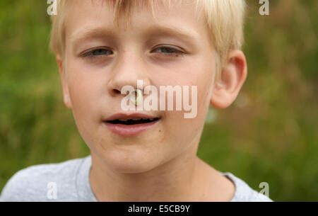 Kind blonde junge mit RHINITIS ohne Gewebe fließt aus der Nase, Porträt, Kopfschuss, Gesicht, detail Stockfoto