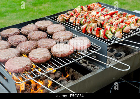 Holzkohlegrill BBQ voller Hähnchenspieße und Beef Burger Stockfoto