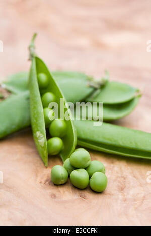 Pisum Sativum. Frisch gepflückt Erbsen auf einem Holzbrett. Stockfoto