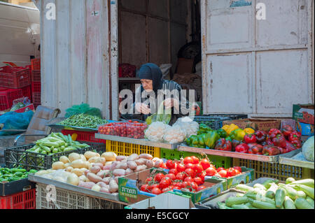 Eine ältere Frau Wahl Gemüse zum Kauf auf dem Markt in der Altstadt von Nazareth, Israel Stockfoto