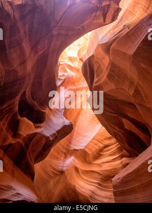 Mittag in einem rot-Orange Antelope Canyon. Ein dünner Strahl des Tageslichtes leuchtet auf dem sandigen Boden des Canyons Stockfoto