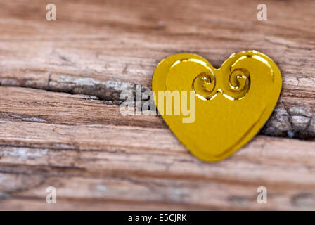 Goldenen Herzchen auf eine rissige Holzbrett liegend Stockfoto