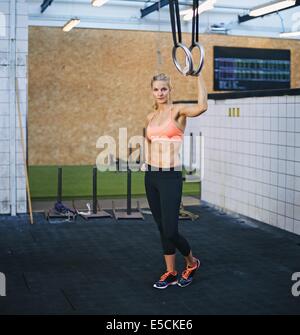 Attraktives weibliches Modell Turnerin Ringe halten. Kaukasische Mädchen in Turnhalle mit Ringen. Stockfoto