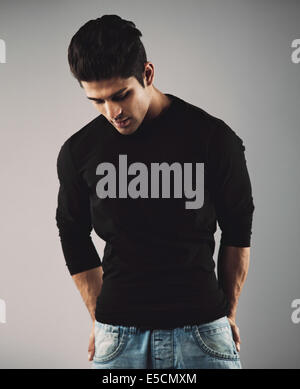 Porträt von hispanic junger Mann stehend auf grauem Hintergrund nach unten denken. Stockfoto