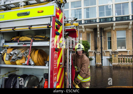 Brighton, East Sussex, UK. 28. Juli 2014. Ein Feuerwehrmann prüft den Schlauch, wie sie versuchen, das Wasser die Überschwemmungen nach unten Keller Schritte hinter ihm sop. Überschwemmungen auf Kingsway Hall Green. Großbritannien Wetter Photo Credit: Julia Claxton/Alamy Live News Stockfoto