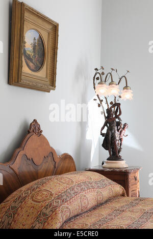 Bett mit Holz-Kopfteil und viktorianischen Lampe auf Beistelltisch. Stockfoto